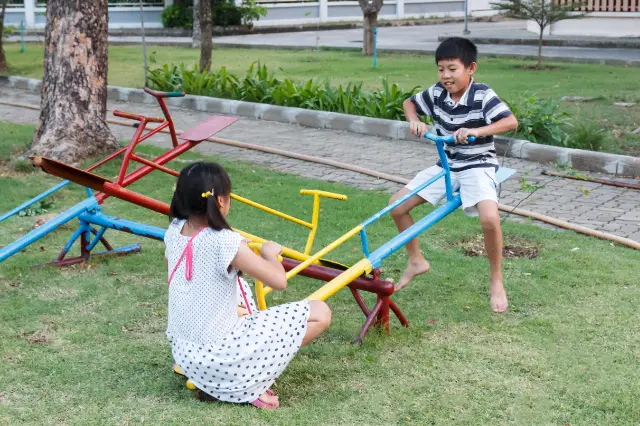 Photo of two children playing on a see-saw (teeter-totter)