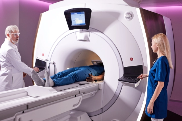 Photo showing a patient inside an MRI scanner, with two medics outside it.